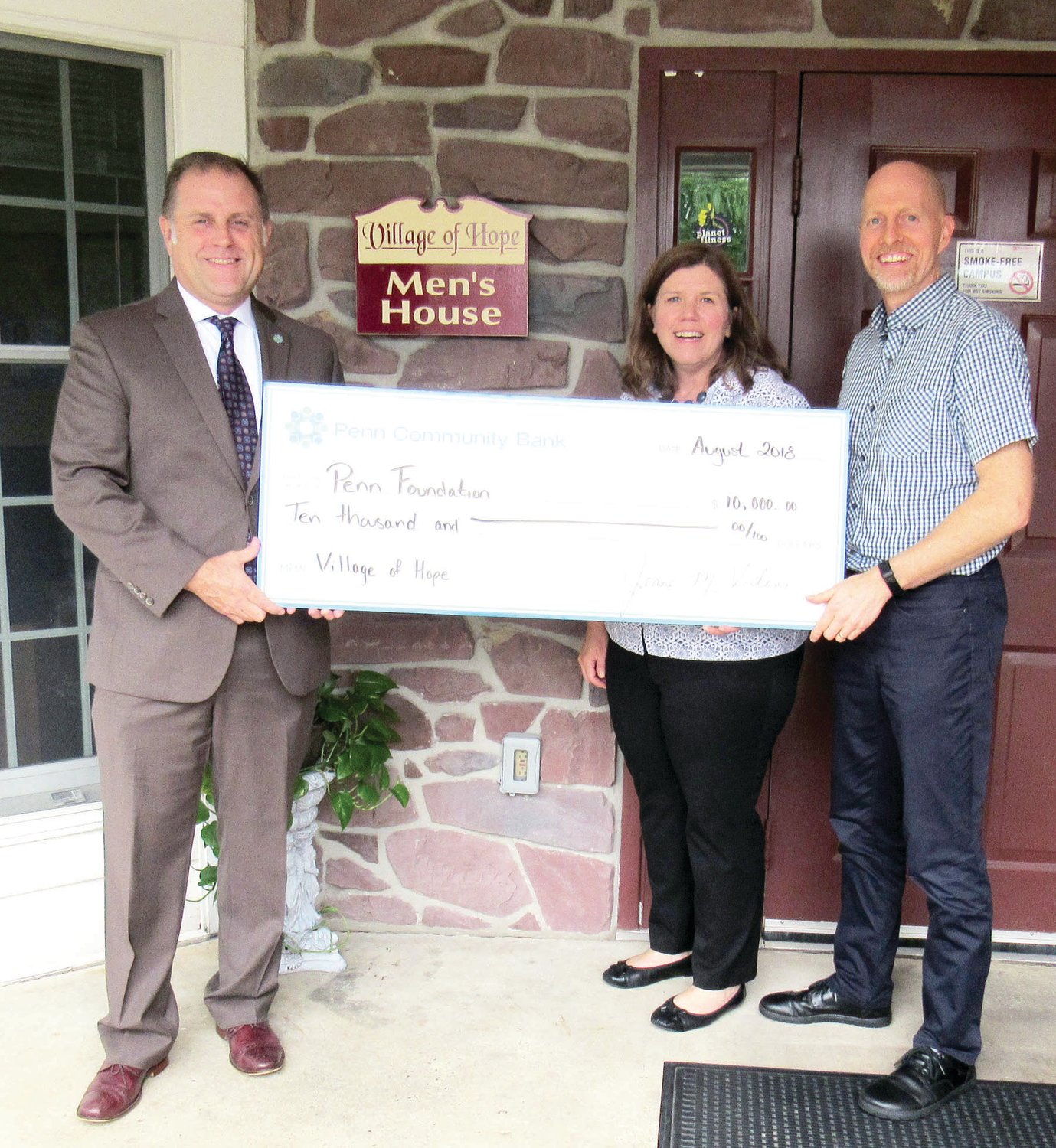 Todd R. Hurley, chief relationship officer at Penn Community Bank, left, presents a check for $10,000 to Jennifer King, director of advancement at Penn Foundation and Don Detweiler, director of the Village of Hope.