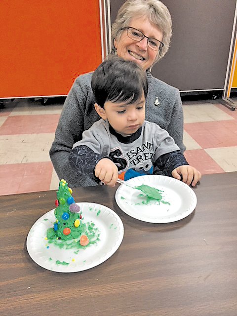 Two-year-old Jordan Grieger, of Riegelsville concentrates on the green frosting, while his grandmother, Sylvia Grieger, provides a little help with his Christmas tree cone. Photograph by Kathryn Finegan Clark