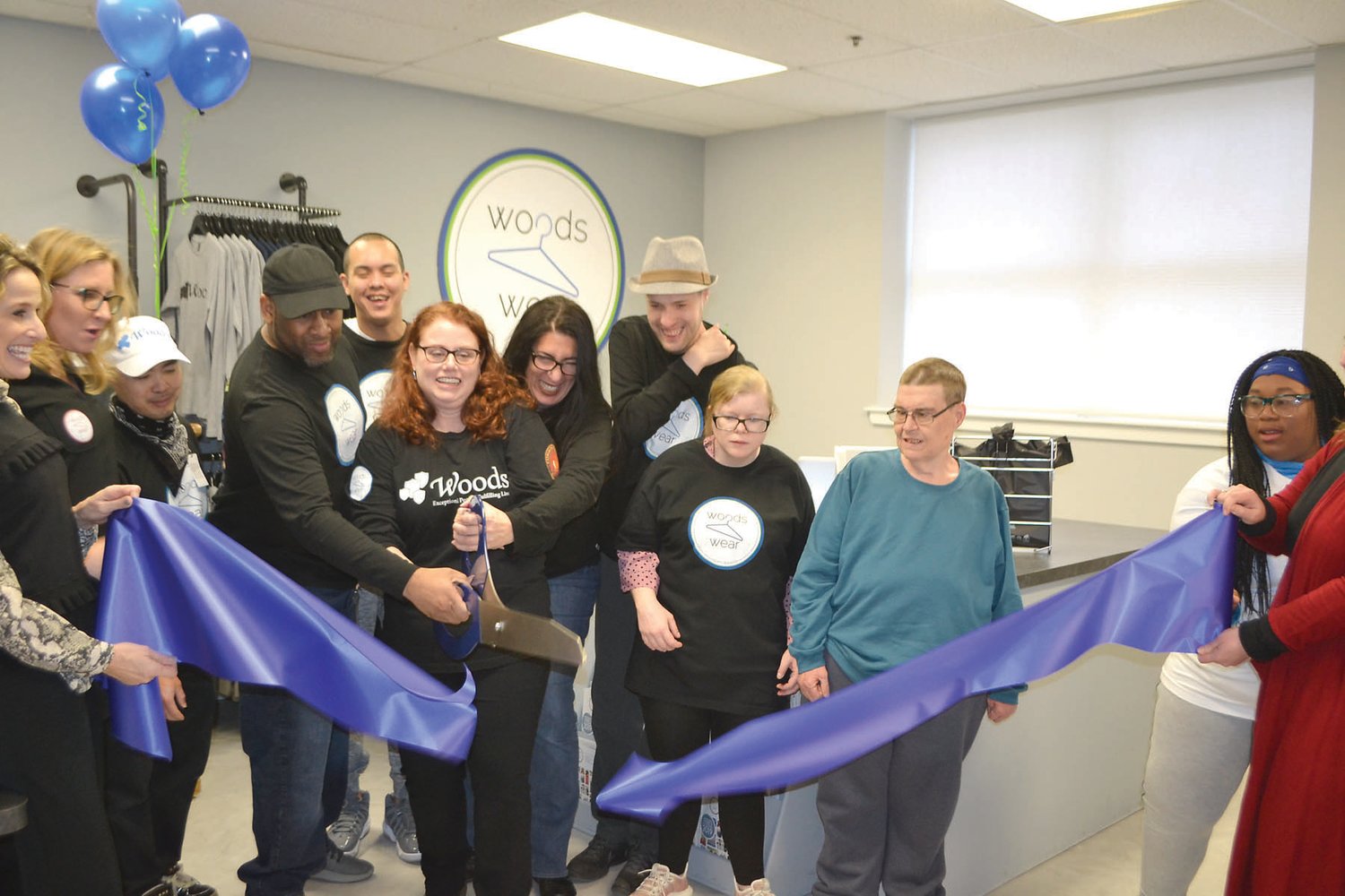 Woods Wear employees help cut the ribbon on the new apparel studio.