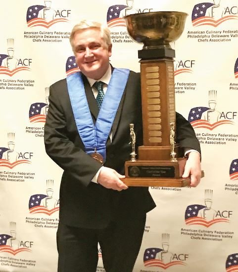 Middle Bucks Institute of Technology culinary arts teacher and educator Michael McCombe stands with the Chef of the Year 2019 trophy.