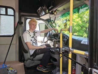 Tim Gibson in the driver’s seat of a 2006 Ford shuttle bus with 98,000 miles on it, which he found on Facebook Marketplace and bought from a Doylestown man. It will be his home for the next six months while he travels the East Coast painting murals.