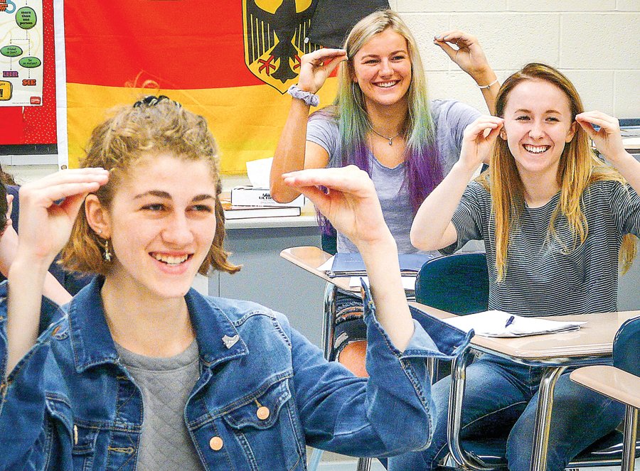 Showing the sign for “teach,” are, from left, Julianna Hinrichsen, Kadie McNally and Morgan Middleberg, students finishing their first year of entry-level American Sign Language.