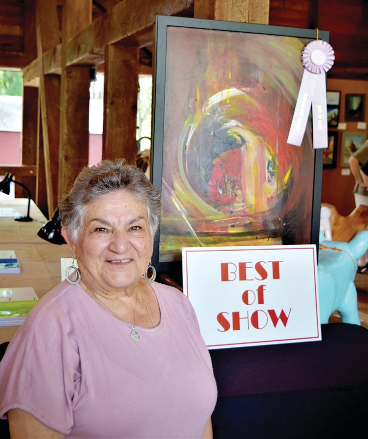Rose Marie Strippoli stands with her Tinicum Arts Festival Art Barn Best of Show award-winning acrylic painting, “The Passage.”