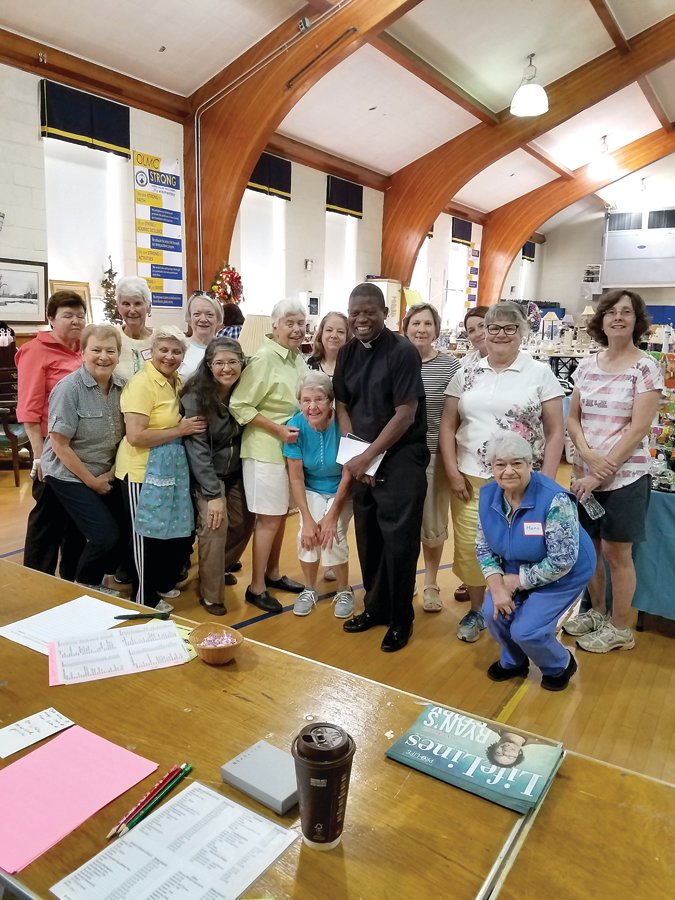 Volunteers gather with the Rev. Paschal Onunwa, parish vicar, OLMC, before the door opens for a prior rummage sale. The next sale is Aug. 7 and 8.