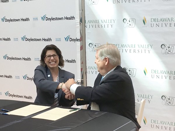 Maria Gallo, president of Delaware Valley University, and Jim Brexler, president and CEO of Doylestown Health, formalize a partnership to advance academic programming and training opportunities in health care.