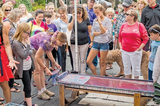 A woman creates her own scarf design at a previous Doylestown Arts Festival as visitors watch.