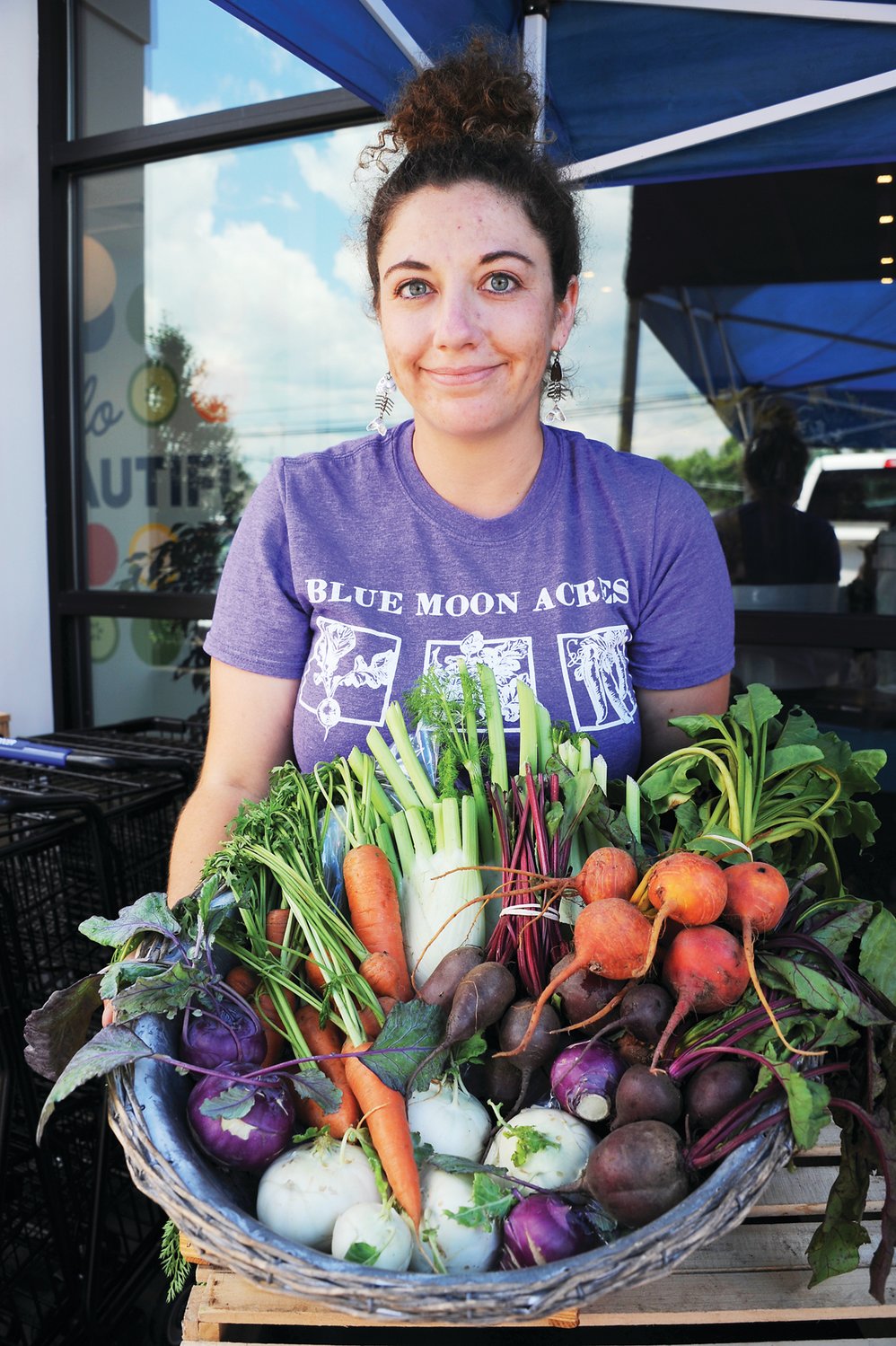 Sara Pavics from Blue Moon Acres showing off local veggies for sale in Poppy’s Greengrocer. Photograph by Carol Ross.