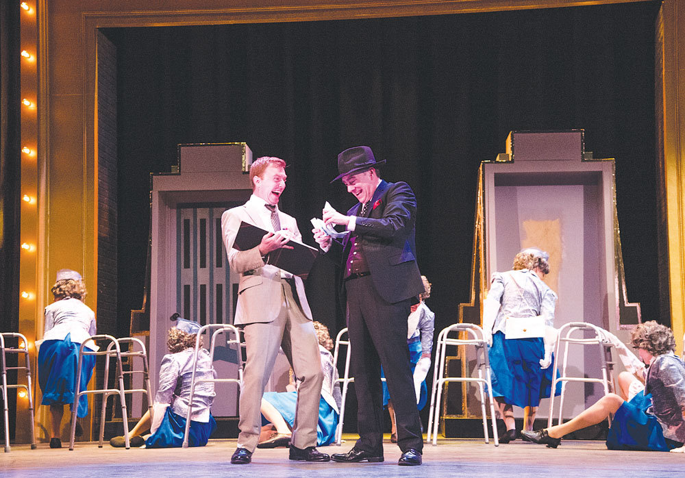 The two leading men, Tony Braithwaite, right, and Zachary Chiero, gleefully count the money donated by the “old ladies” Max Bialystock flatters to raise funds to produce “Springtime for Hitler” in the “The Producers,” now playing at Delaware Valley University and performed by the Bucks County Center for the Performing Arts. The “old ladies” have just executed the famous walker dance in the show.