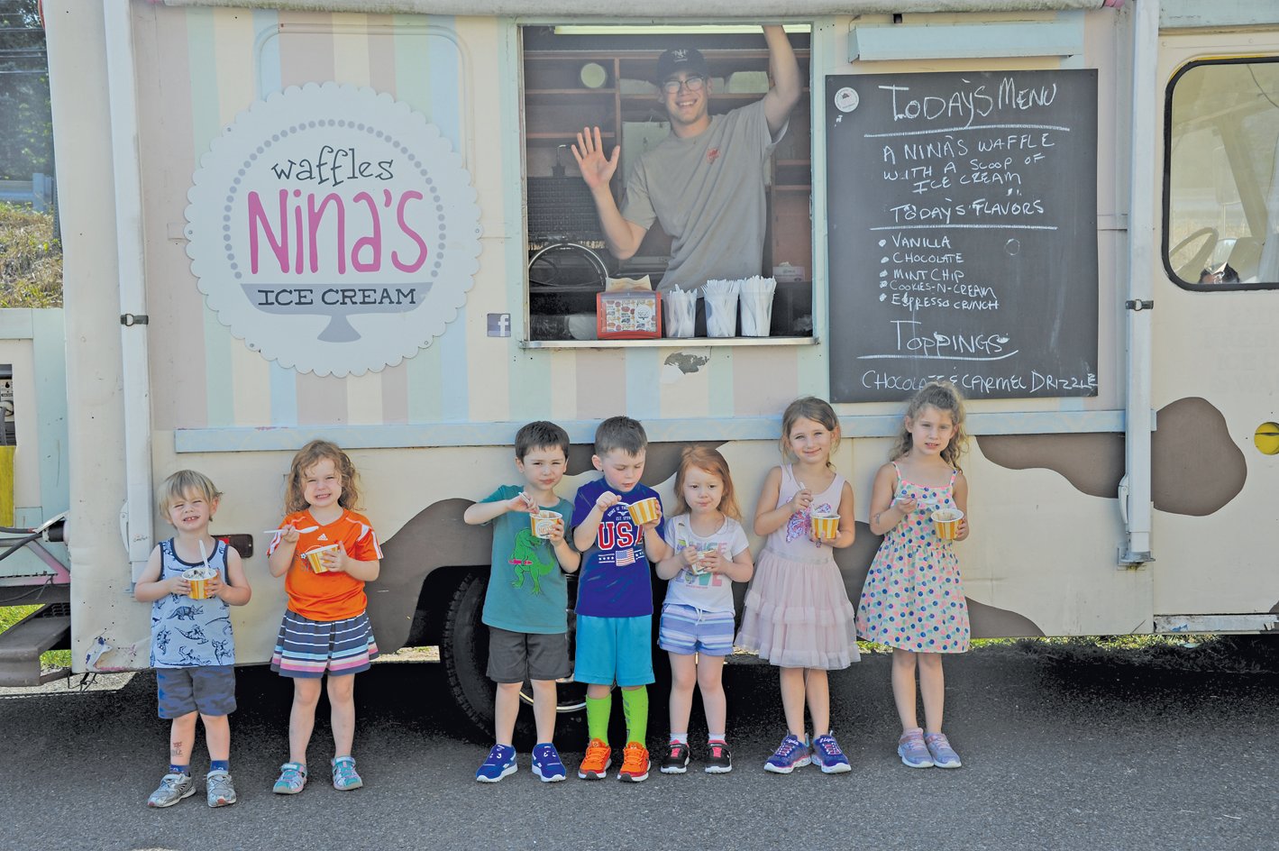 Mikey Duncan from Nina’s Ice Cream gives a wave as youngsters dig into their ice cream. Photograph by Carol Ross.