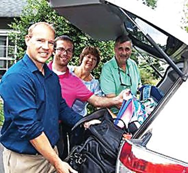 Bucks County Housing Group officials, from left, Erik Clare and Nicholas Parsons, with help from St. Andrews Episcopal Church parishioners Cindy and Bill Vallier, load backpacks donated by church members.
