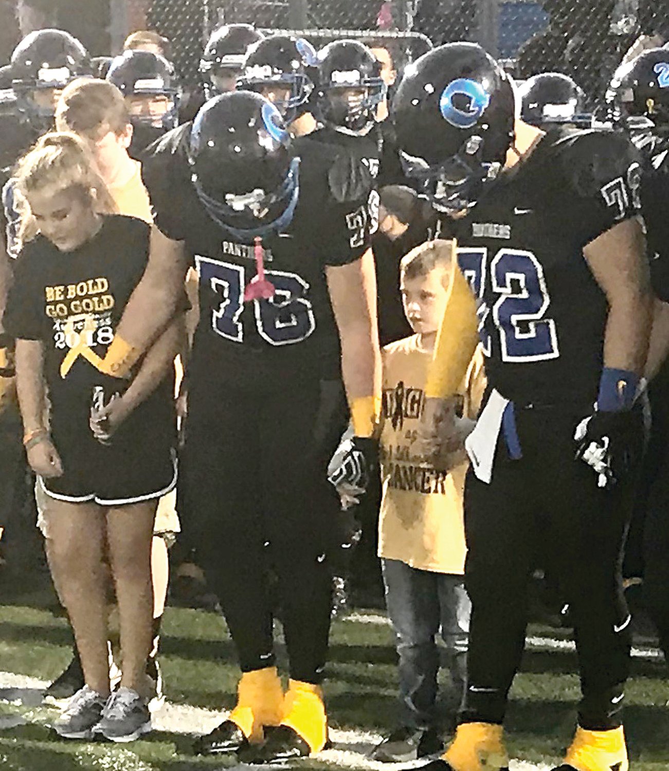 Quakertown Community High School football captains Logan Banas, No. 72, and Shawn Newswanger get ready to walk to midfield for the coin toss with Maddie Willing, left, and Rhiley Coughlin. Last Friday was not only Quakertown’s 500th win, but also Childhood Cancer Awareness Night. Read more about the team’s and school community’s efforts to raise awareness on page B3.