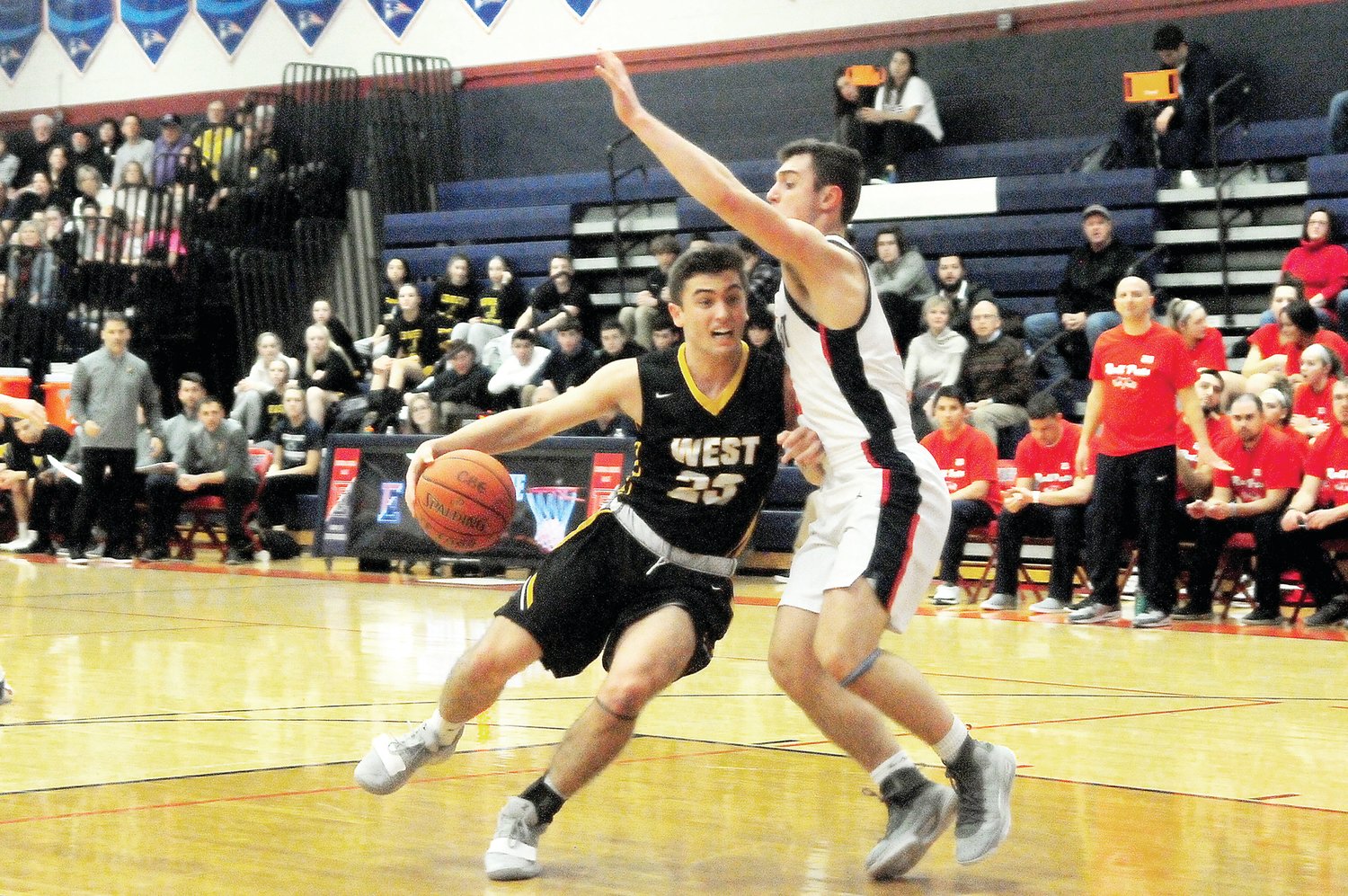 CB West senior Owen Haney, 23, left, drives the ball into the lane defended by CB East junior Joe Jackman in the Patriots’ win over the Bucks Jan. 17 at CB East. Photograph by Steve Sherman.