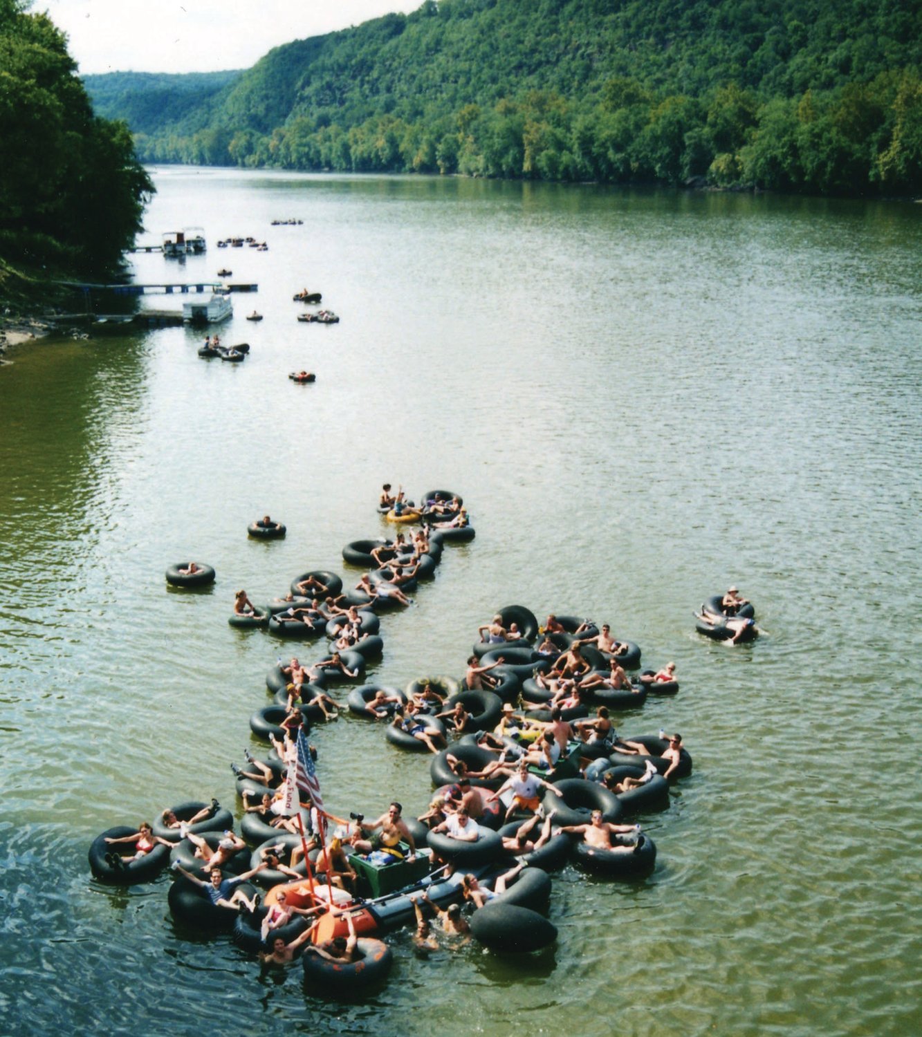 “Tube heads” float down the Delaware River, interconnected and latched onto the “river barge” (bottom with flag).