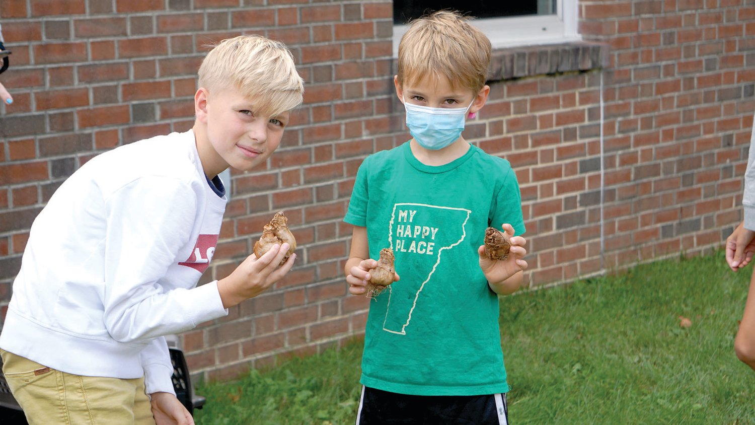 Two Kutz Elementary students hold up daffodil bulbs to be planted around the school’s flagpole.
