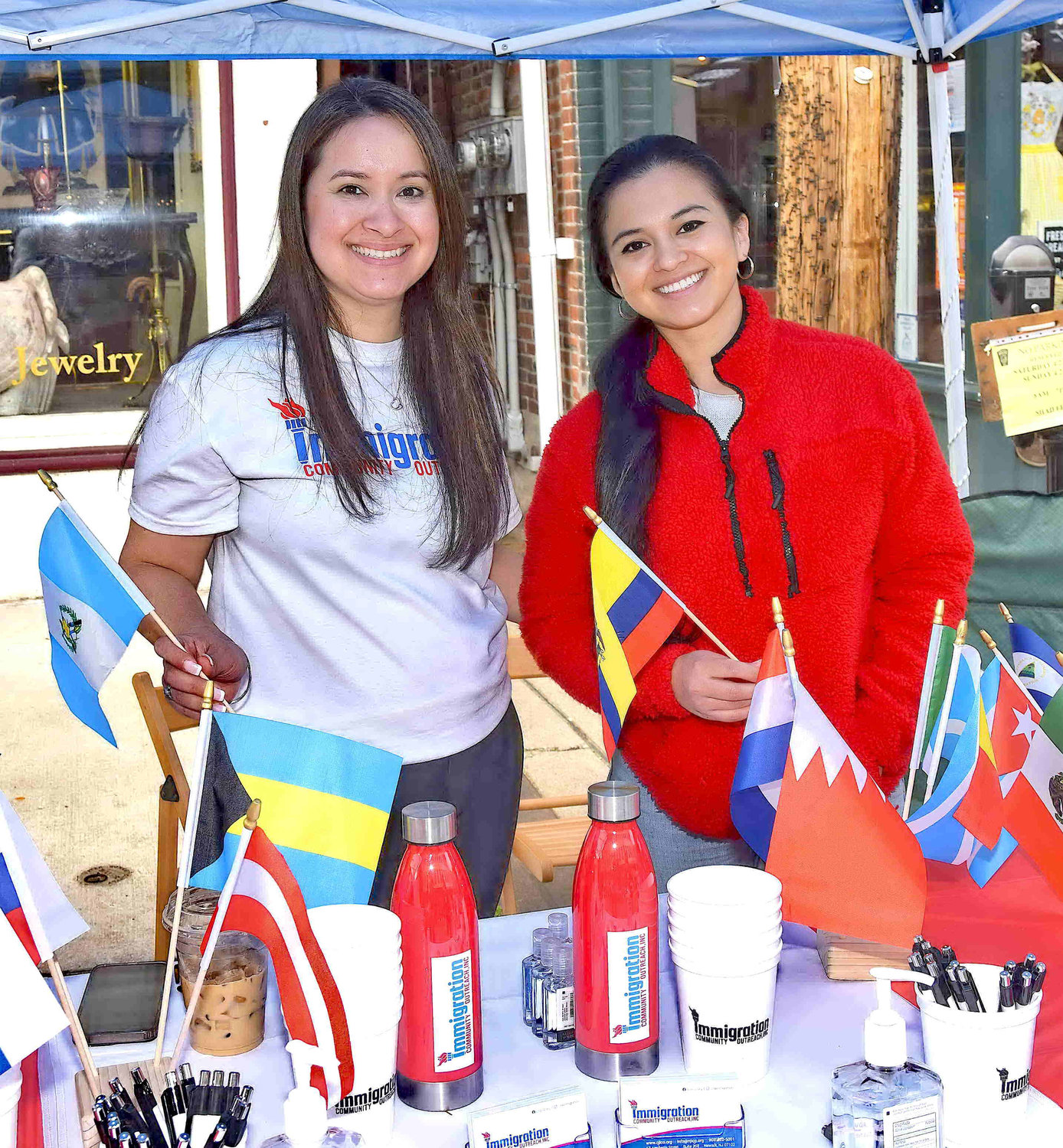 Maira Lamantia and Tahana Intriago of Immigration Community Outreach with flags from many countries.