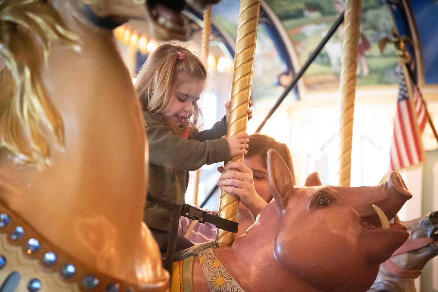 Aubrey Donaldson, 2, of Newark, Del., who was in the area visiting her grandpop last Sunday, takes a ride on the merry-go-round pig at Giggleberry Fair in Peddler’s Village, Lahaska, which has been hosting a Summer Block Party every weekend through the month of June.