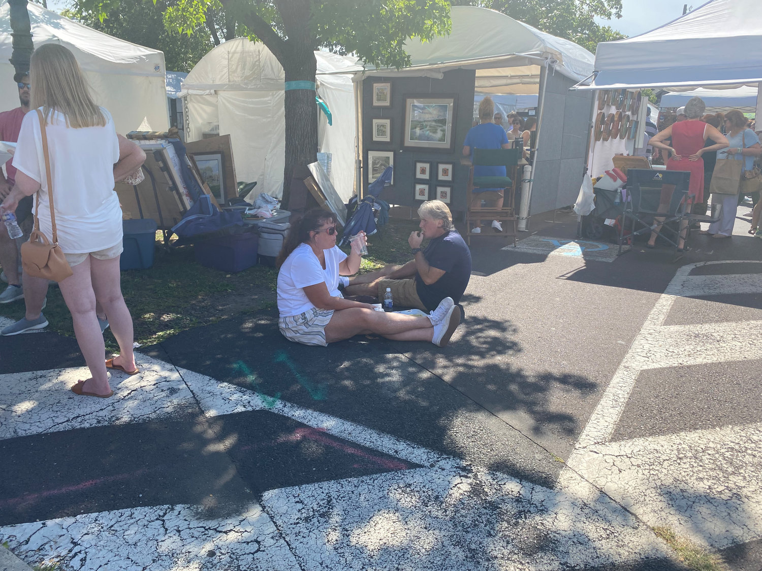 A couple takes a break from the bright sun and crowded streets at the Doylestown Arts Festival to enjoy a cold drink and a bite to eat.