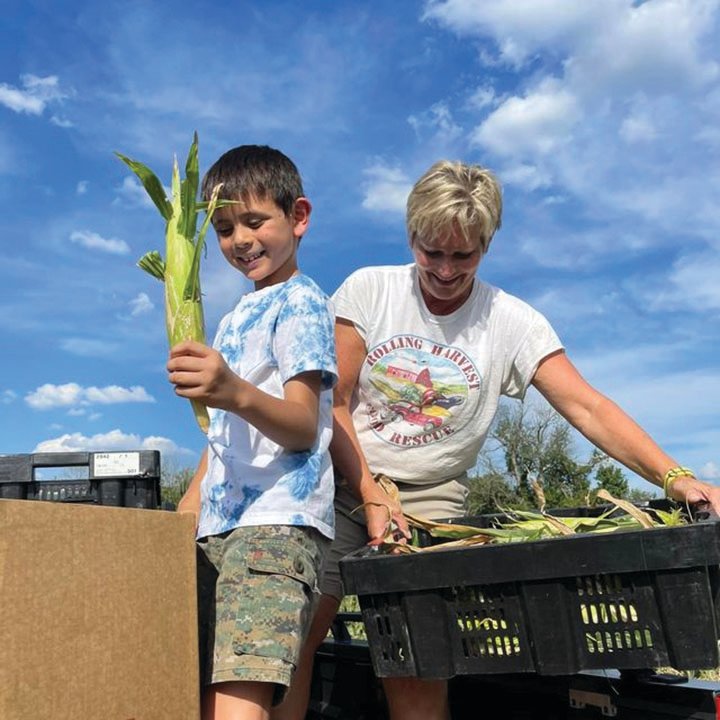 Rolling Harvest Program Director Jamie McKnight gleans sweet corn from a partner farm in Doylestown with help from 8-year-old Theo Li Seliger.