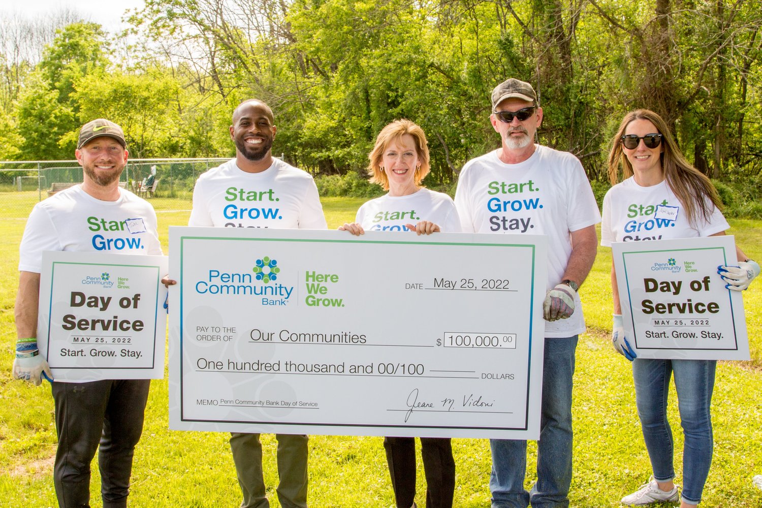 Employees hold signs and a ceremonial check reflecting Penn Community Bank’s Day of Service.