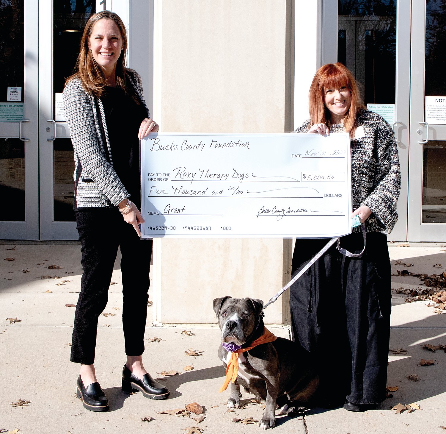 Mandy Munday, executive director of the Bucks County Foundation, presents a check for $5,000 to Roxy Therapy Dogs President Sharon Fleck, as Bleu, Flecks’ Roxy dog, looks on.