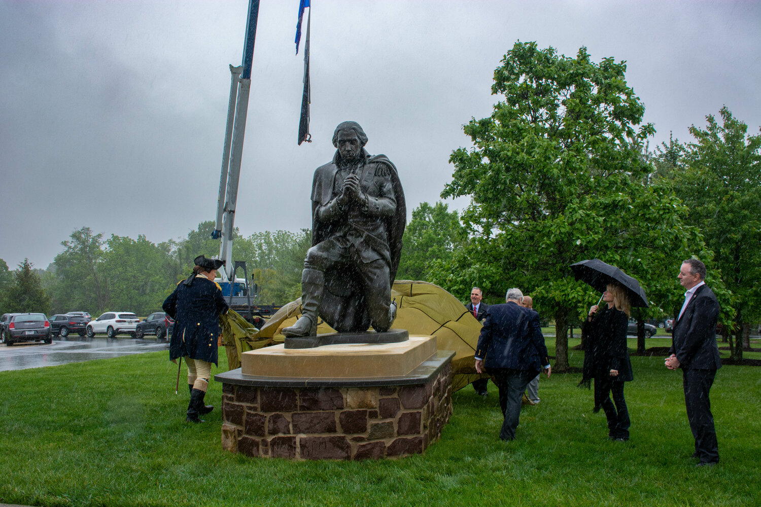 Langhorne Borough Police Chief John Godzieba, left, portraying George Washington, helps remove the tarp that covered a new statue of the founder of our nation at its dedication ceremony Saturday at Washington Crossing National Cemetery in Bucks County. U.S. Rep. Brian Fitzpatrick, far right, looks on.