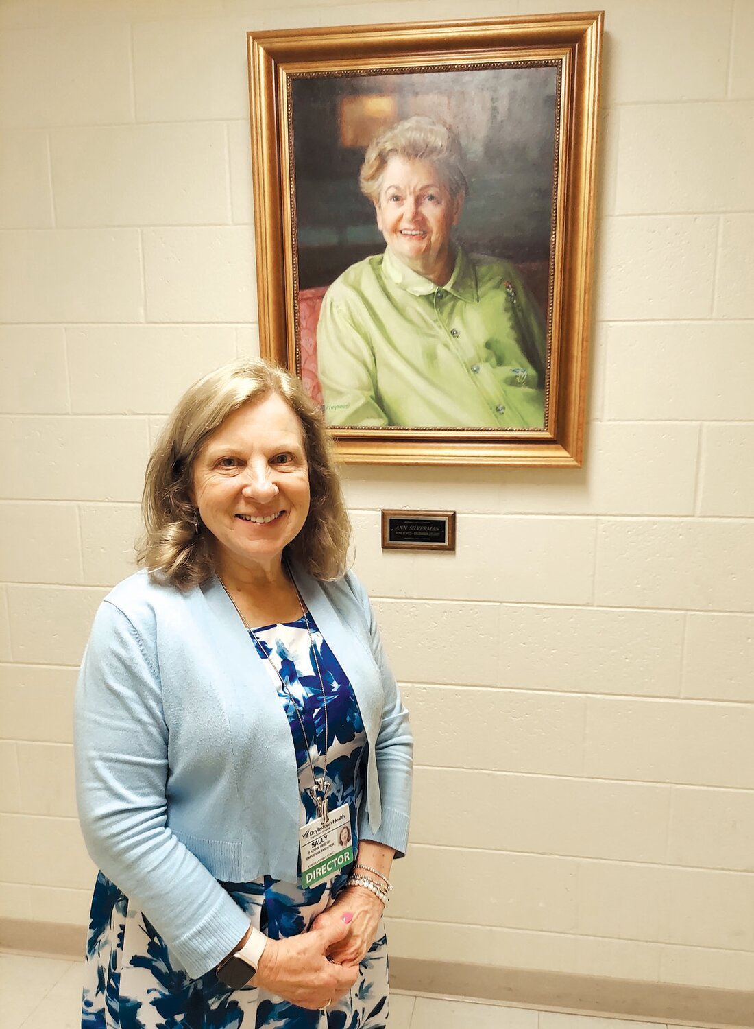 Sally Fabian Oresic stands by a portrait of Ann Silverman at the entrance to the Ann Silverman Clinic.
