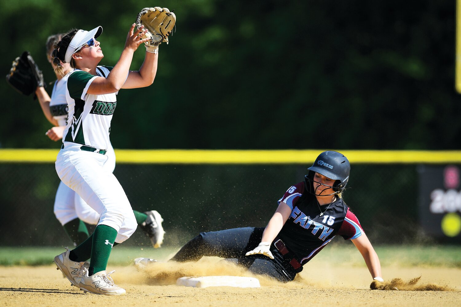 Faith Christian’s Lexi Reed slides in ahead of the throw in front of Dock Mennonite’s Addison Landis during the third inning.