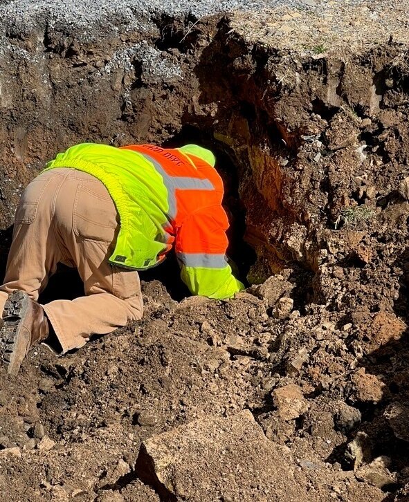 Assistant roadmaster peeks his head inside the hole Durham Township Roadmaster Peter Cox discovered while taking soil samples.
