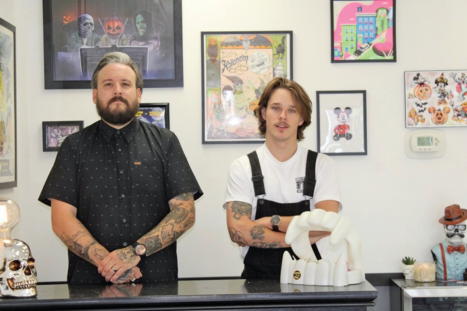Diehl Mollica and Luke Pomper stand behind the counter of Happily Haunted Barbershop.