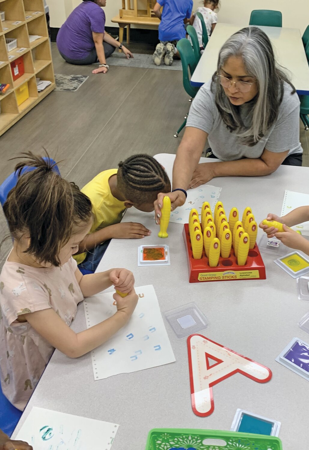Head pre-k teacher Sharon O’Neill guides letter-stamping with brand new pre-k students at the Child Learning Center.
