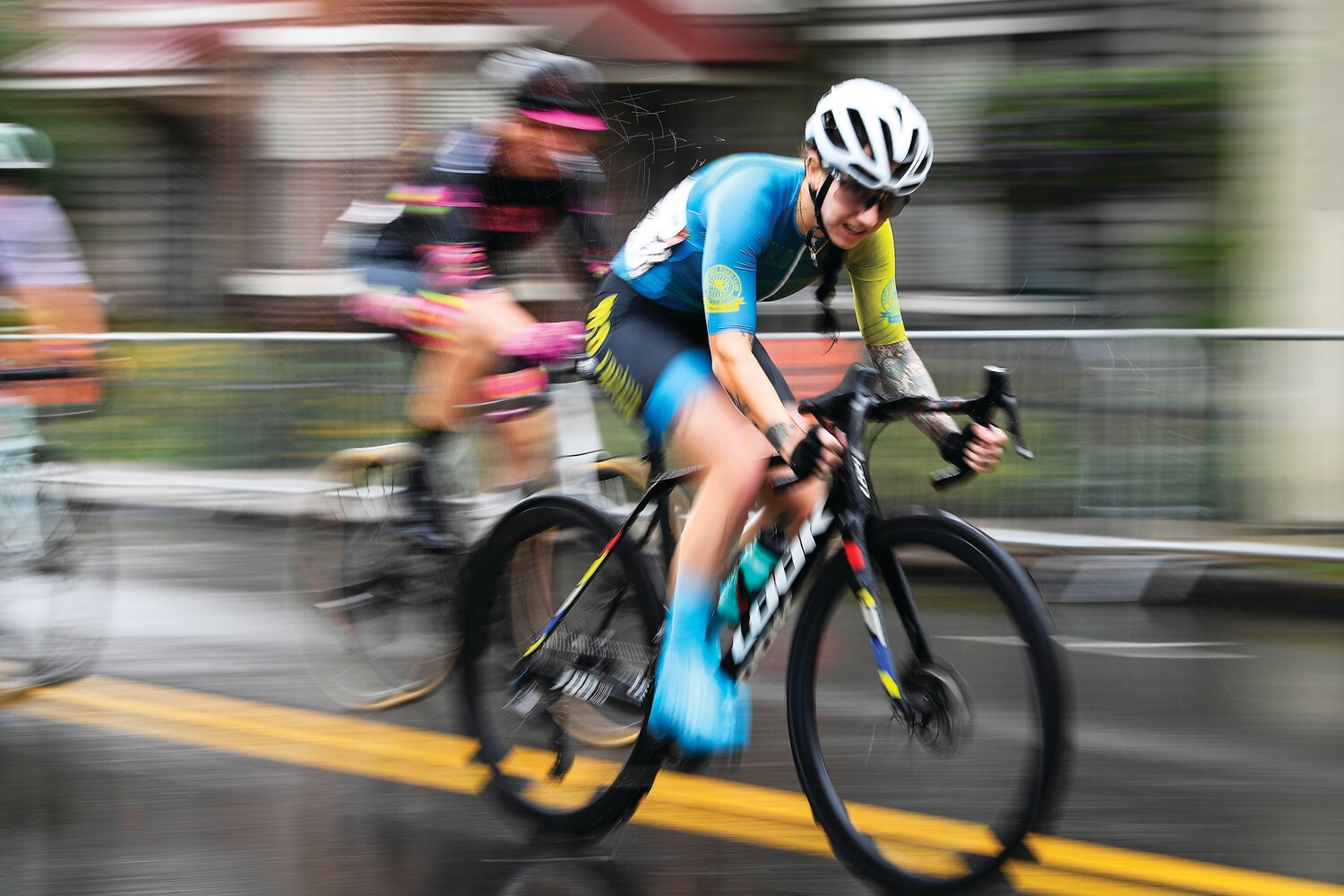 Category 3/4 women’s race winner Natalie Gulla speeds through the rain-soaked streets.